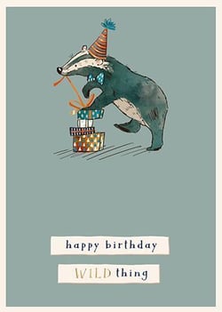 A badger, wearing a party hat, is standing atop a stack of presents.
