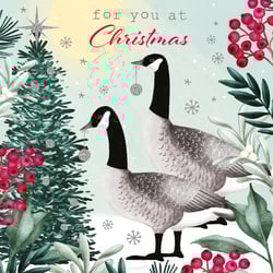 A Christmas card with two geese in front of a Christmas tree.