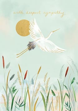 a white crane is flying over a field of tall grass .