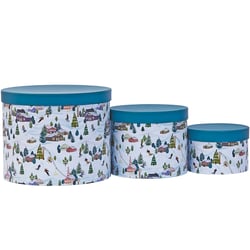 three round boxes with a snowy scene on them