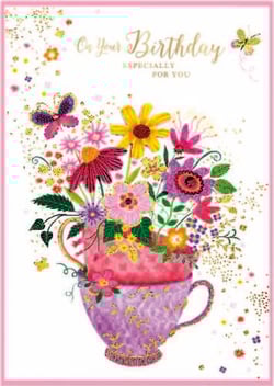 a birthday card with a teacup filled with flowers and butterflies .