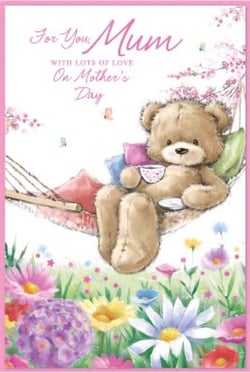 a teddy bear is sitting in a hammock holding a cup of tea .