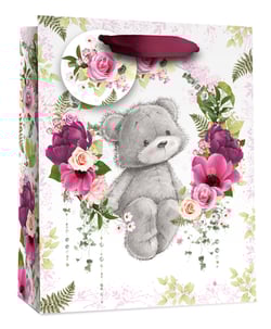 a gift bag with a teddy bear surrounded by pink flowers