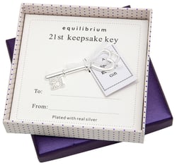 a silver key in a box that says equilibrium 21st keepsake key