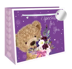 Make every gift extra special with our Extra Large Bear Bouquet Shopper Gift Bag. This delightful bag features an adorable fluffy teddy bear peeking out, holding a beautiful bouquet of rich purple, burgundy, and white flowers, tied with a sweet pink bow. The vibrant purple background, adorned with subtle hearts and patterns, carries the heartfelt message 'Especially for You'. With elegant lilac side panels featuring delicate heart detailing, this extra-large bag is perfect for presenting those memorable gifts. Offer your customers premium, charming gift packaging. Available in a convenient pack of 6 from Out of The Blue Studios Ltd.