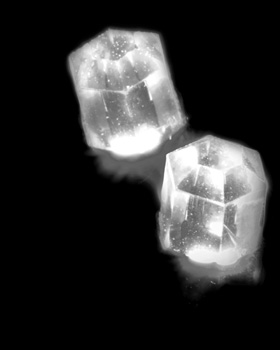 Two ice cubes are floating in the air against a black background.