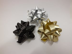 Black, silver, and gold bows are on a white surface.