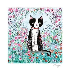 A black and white cat are sitting in a field of flowers.