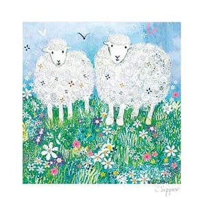 Three sheep stand in a field of flowers.