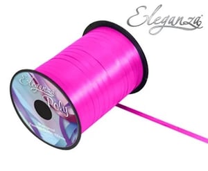 A spool of pink ribbon is sitting on a white surface.