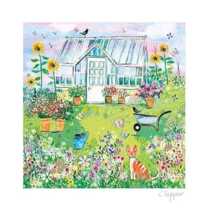A cat is sitting in front of the greenhouse in the garden.