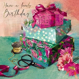 a birthday card with a stack of gifts and flowers on a table .