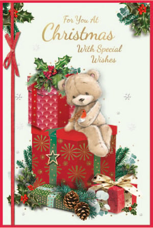 a christmas card with a teddy bear sitting on a pile of presents