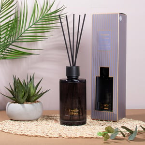 a desire home reed diffuser sits on a table next to a plant