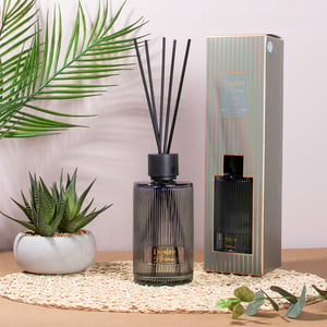 a desire home reed diffuser sits on a table next to a plant