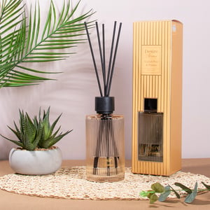 a desire home reed diffuser sits on a table next to a plant