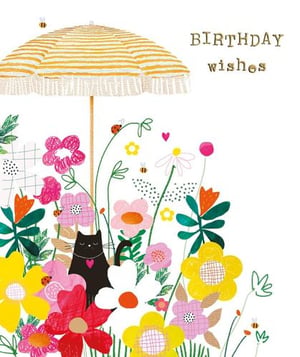 a black cat is sitting under an umbrella in a field of flowers .