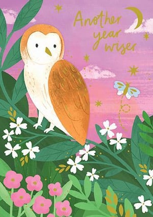 an owl is sitting on a branch in a field of flowers .
