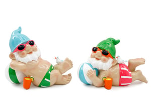 two figurines of gnomes laying on a beach