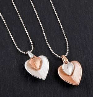 two necklaces with hearts on them on a black surface