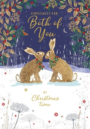 Offer your customers a truly enchanting Christmas card with our 'To Both Of You' design from Nigel Quiney Publications. This delightful card features two golden-hued hares, lovingly adorned with festive wreaths, sharing a tender moment in a serene, snow-dusted landscape. Above them, a deep blue, star-speckled sky is framed by elegant golden foliage and rich red berries, hinting at a magical winter's night. The exquisite gold foil detailing throughout adds a luxurious shimmer, making this the perfect choice for couples. Each pack contains 6 cards, ensuring your shelves are stocked with this heartwarming design.
