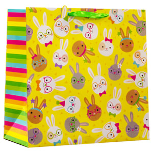 Make Easter gifting a delight with our Large Easter Bunnies Gift Bag! This vibrant bag features a cheerful yellow background, playfully adorned with an array of adorable, diverse bunny faces. Each bunny boasts its own unique style, from playful glasses and bows to festive party hats. The brightly striped side panel adds an extra pop of colour, complemented by a sturdy green ribbon handle. Perfect for holding all sorts of Easter treats and presents, these bags are sure to bring smiles. Available in a convenient wholesale pack of 6.