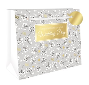 Celebrate their special day in style with our Extra Large Wedding Day Blossom Shopper Gift Bag. This exquisite bag features a soft grey background, beautifully adorned with delicate white blossom patterns. Shimmering gold accents, including wedding rings, hearts, horseshoes, and butterflies, add a touch of romance and good fortune. A prominent gold plaque elegantly displays "Congratulations on your Wedding Day" in a sophisticated script. Complete with sturdy white ribbon handles and a charming gold gift tag, this extra-large bag is perfect for presenting generous wedding gifts. Supplied by Out of The Blue Studios Ltd., these stunning bags are available in a convenient pack of 6, ensuring you're ready for every celebration. Give your customers the perfect finishing touch for their wedding presents.