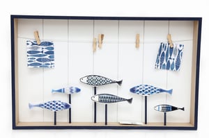 Bring a wave of coastal charm into any home with our delightful Fish Hanging Peg Board. This beautifully designed decorative piece features a crisp white background, framed elegantly in navy. It showcases an enchanting collection of blue and white patterned fish, each artfully displayed on individual stands, creating a serene underwater scene.
The integrated string and wooden pegs offer a practical and charming way to display cherished photos, notes, or small mementos. Perfect for adding a refreshing seaside vibe to living spaces, children's rooms, or even a home office, this versatile peg board is a wonderful addition to any decor collection. It's sure to be a popular item for customers seeking unique and stylish accents.