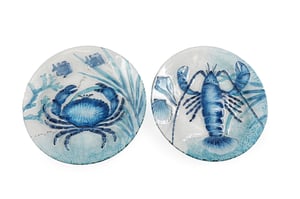 Bring the charm of the seaside to your customers' homes with these stunning 30cm Crab/Lobster Glass Plates. Each plate features an intricately detailed blue marine creature – one a majestic crab, the other a striking lobster – set against a backdrop of delicate aquatic flora and shells.
Crafted from high-quality glass, these plates boast a beautiful textured finish that adds depth and character to their vibrant blue and white design. Perfect for serving appetisers, displaying as decorative pieces, or simply adding a touch of coastal elegance to any table setting. Sold in a convenient pack of four, these plates are sure to be a popular choice for those looking to infuse their decor with a breath of fresh ocean air.