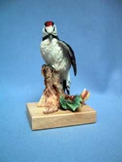 A statue of a bird sits on a tree branch.