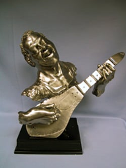 A bronze statue of a man playing guitar.
