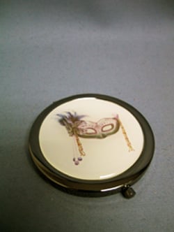 A round mirror with a picture of a mask on it.