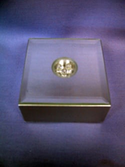 A square glass box with a gold circle is on top.