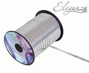 A spool of silver ribbon is sitting on the white surface.