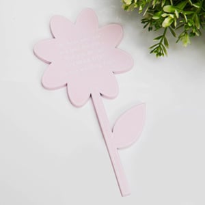 A pink flower rests with a leaf on a white surface.