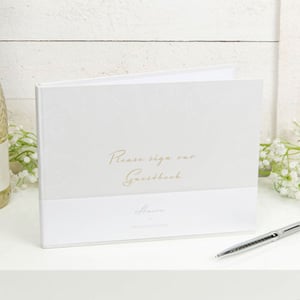 A white guestbook with the words "Please sign our guestbook" written on it.