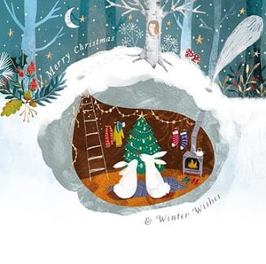 Two rabbits are sitting in a cave with a Christmas tree.