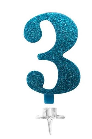 A blue glitter birthday candle in the shape of the number three on a white background.