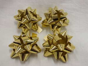 Four gold bows is sitting on a white surface.