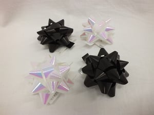 Four differently colored bows are sitting on a white surface.