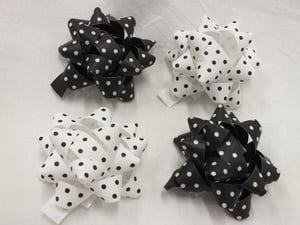 Four black and white polka dot bows are on a white surface.