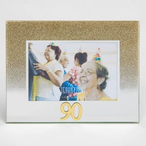 A picture frame with a picture of an elderly woman wearing a party hat.