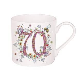 A white mug with the number 70 is surrounded by flowers and butterflies.