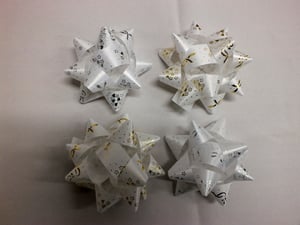 There are four white and gold bows on a white surface.