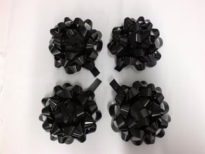 Four black bows are on a white surface.