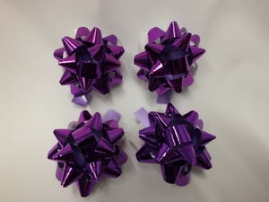 Four purple bows is on a white surface.