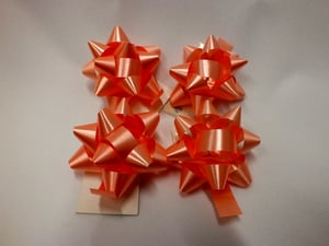 Four orange bows is sitting on a white surface.