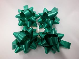 Four green bows is sitting on a white surface.