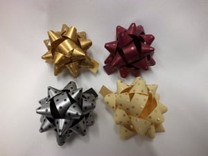Four differently colored bows are on a white surface.