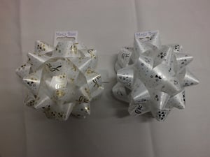 Two white and gold bows with a tag that say magic bow.
